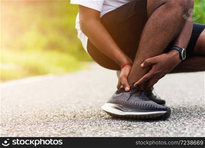 Close up Asian young sport runner black man wear watch hands joint hold leg pain because of twisted ankle broken while running at the outdoor street health park, healthy exercise Injury from workout
