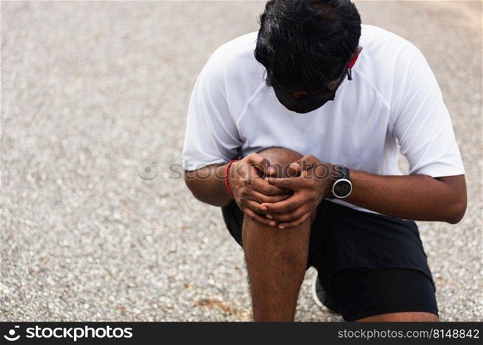 Close up Asian young sport runner black man wear watch sitting hands joint hold knee pain during the run while running at the outdoor street health park, healthy exercise injury from workout concept