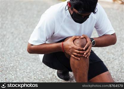 Close up Asian young sport runner black man wear watch sitting hands joint hold knee pain during the run while running at the outdoor street health park, healthy exercise injury from workout concept