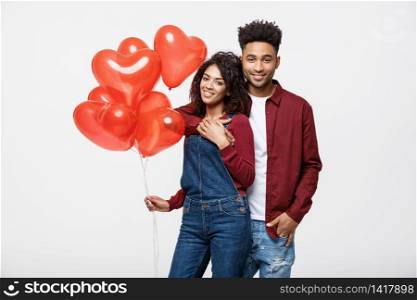 Close up attractive African American couple huging and holding red heart balloon. Close up attractive African American couple huging and holding red heart balloon.