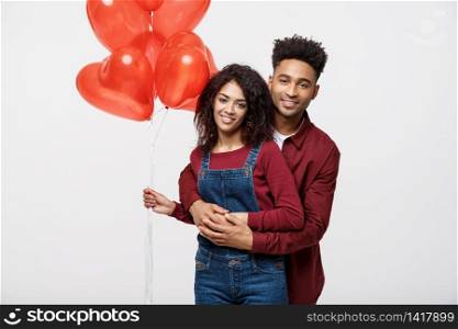 Close up attractive African American couple huging and holding red heart balloon. Close up attractive African American couple huging and holding red heart balloon.