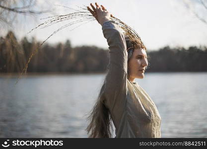 Close up authentic woman running hand up willow twigs crown portrait picture. Closeup side view photography with blurred background. High quality photo for ads, travel blog, magazine, article. Close up authentic woman running hand up willow twigs crown portrait picture