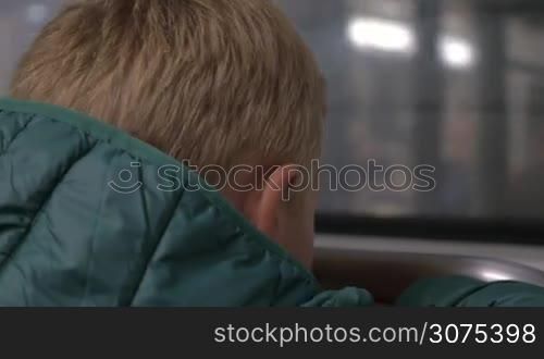 Close-up back shot of a child looking through the window of moving underground train