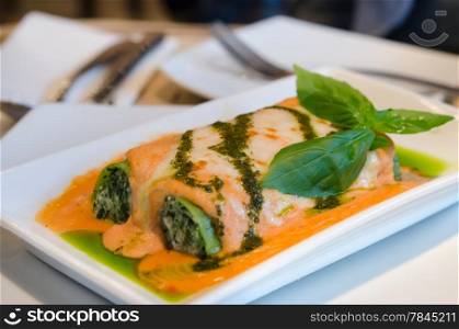 close up Baked Lasagna Rolled With Spinach Ricotta Cream Topped With Sweet Capsicum & Pesto Sauce