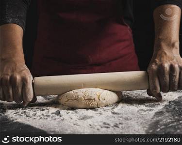close up baker rolling dough composition
