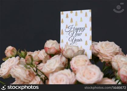 Close up beautiful Fresh pink roses flowers with Happy New Year greeting card on grey background. copy space. Close up beautiful Fresh pink roses flowers with Happy New Year greeting card on grey background. copy space.
