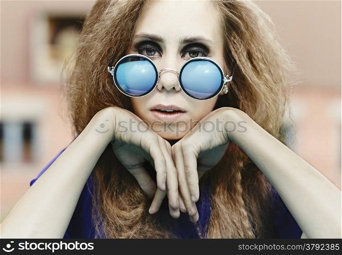 Close up, beautiful hippie girl wearing a mirrored sunglasses and leans against her arms, cross processed retro effect