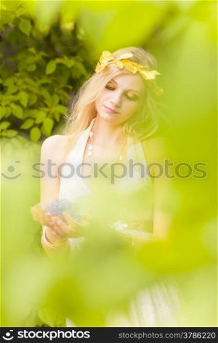 Close-up - beautiful makeup girl wearing white tunic and an antique jewels, green leaves around