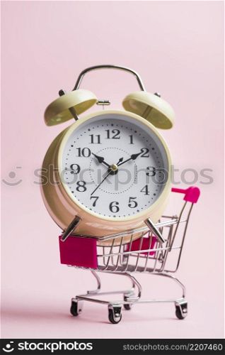 close up big alarm clock trolley pink background