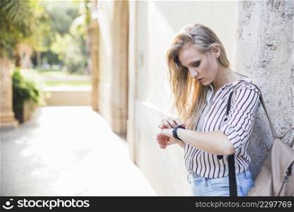 close up blonde young woman checking her time watch