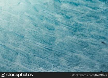 Close up blue wavy ice surface concept photo. Winter season. Top view photography with frozen water on background. High quality picture for wallpaper, travel blog, magazine, article. Close up blue wavy ice surface concept photo