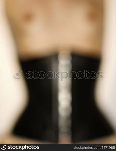 Close up blurred nude of young Caucasian woman wearing corset.