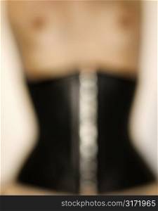 Close up blurred nude of young Caucasian woman wearing corset.