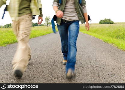 Close-up blurred portrait hiking couple legs backpack on asphalt road