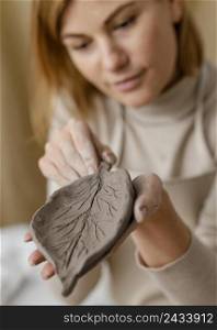 close up blurry woman holding clay leaf