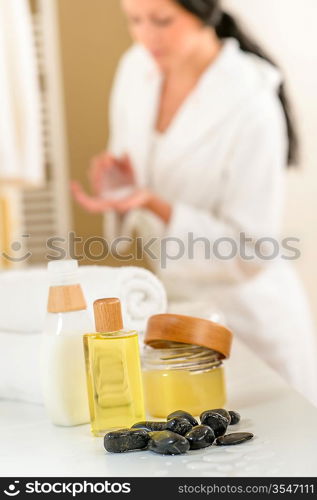 Close-up body care products in bathroom with woman in background