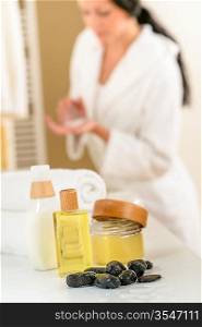 Close-up body care products in bathroom with woman in background