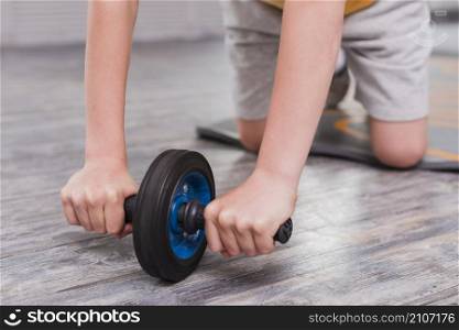 close up boy kneeling exercising with roller slide