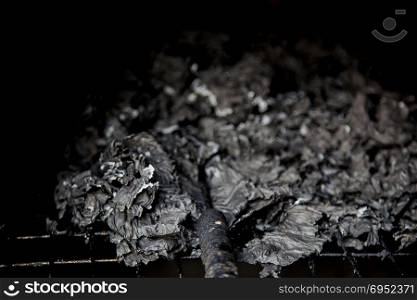 close up burned paper in hold prying in dark