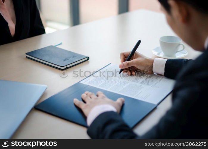 Close up business man writing or signing contract on paper in office.