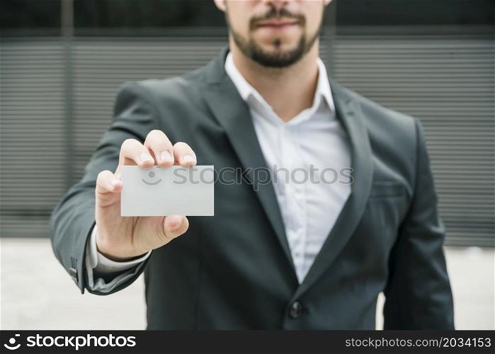 close up businessman standing outdoors showing blank white business card