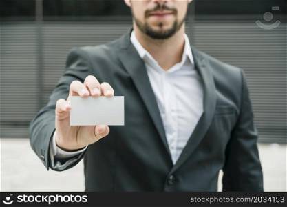 close up businessman standing outdoors showing blank white business card