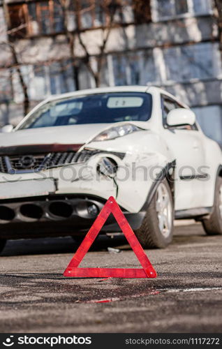 Close up car emergency stop sign on the road. Car accident or accident. The front fender and right headlight are broken, damaged and scratched on the bumper.. Close up car emergency stop sign on the road. The front fender and right headlight are broken, damaged and scratched on the bumper.