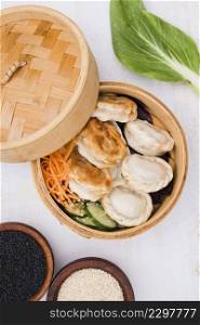 close up chinese steamed dumplings with salad steamer basket with black white sesame seeds