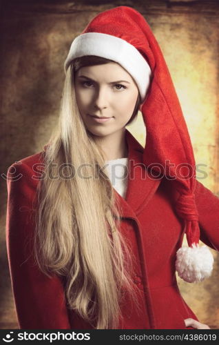 close-up christmas portrait of pretty blonde fashion woman. She smiling and wearing red winter coat and santa claus hat