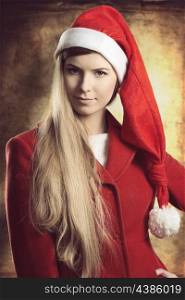close-up christmas portrait of pretty blonde fashion woman. She smiling and wearing red winter coat and santa claus hat