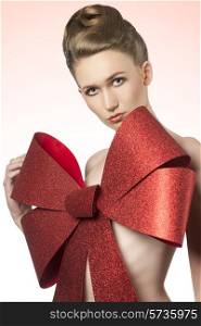 close-up christmas shoot of naked girl with elegant hair-style and big glitter red bow on her breast