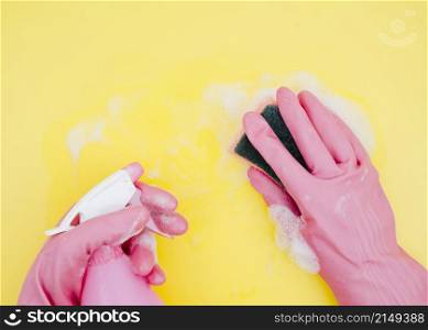 close up cleaner cleaning yellow backdrop with sponge spray bottle