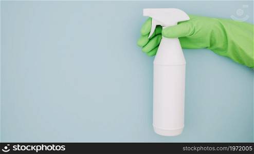 close up cleaner s hand wearing green gloves holding white spray bottle blue backdrop. High resolution photo. close up cleaner s hand wearing green gloves holding white spray bottle blue backdrop. High quality photo