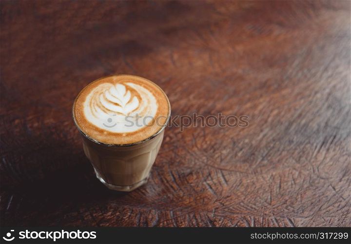 Close up coffee cup with latte art on grunge wood table at cafe