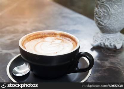 Close up coffee latte art in black cup on marble texture, Luxury and lifestyle concept