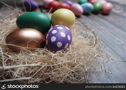 Close up colorful Easter eggs in nest on wooden table