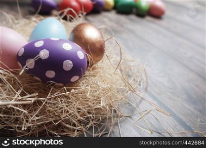 Close up colorful Easter eggs in nest on wooden table