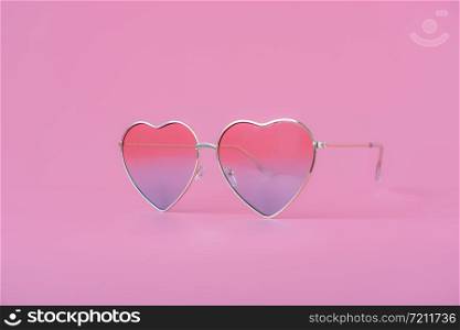 Close up colorful love shape sunglasses on modern rustic pink paper background.pastel tone design & fashion summer concept background. valentine day.