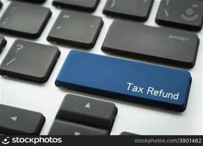 Close up computer keyboard focus on a blue button with typographic word Tax Refund.