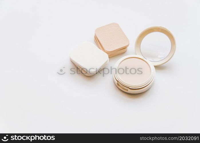 close up cosmetic realistic plastic compact powder with sponges white backdrop