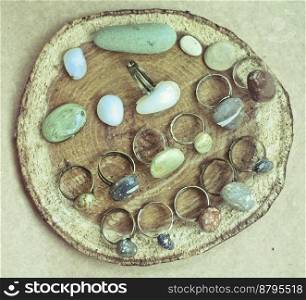Close up craft rings with natural stones on stub concept photo. Top view photography with plywood sheet on background. High quality picture for wallpaper, travel blog, magazine, article. Close up craft rings with natural stones on stub concept photo