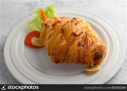 Close up croissant with hotdog on white dish and decoration with tomato sliced, carrot and lettuce beautifully, copy space