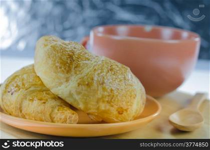 close up croissants on brown dish and a cup of coffee