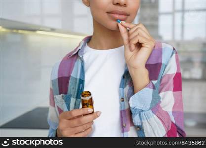 Close up cropped young girl holding pill and jar of medicine, taking medication, vitamins, sedatives, or dietary supplement. Female takes tablet for woman skin hair health, vitamin deficiency prevent.. Close up young girl holding pills, taking vitamins, dietary supplement for woman skin hair health