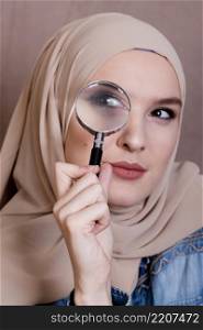 close up curious muslim woman looking through magnifying glass
