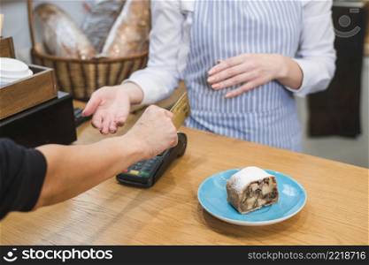 close up customer using payment terminal paying bill pastry