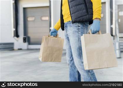 close up delivery man holding paper bags