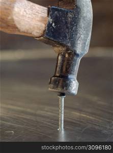 Close up detail of hammer hammering a nail into metal