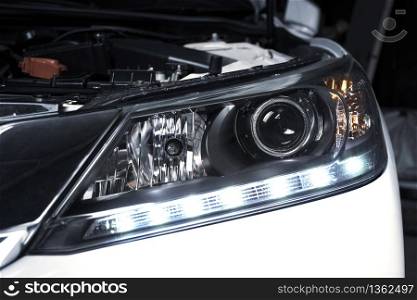 Close up details of projector lens headlights and daytime running light technology in a car.