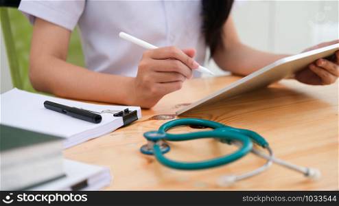 Close up doctor examining medical report while using computer tablet. Medical and healthcare concept.